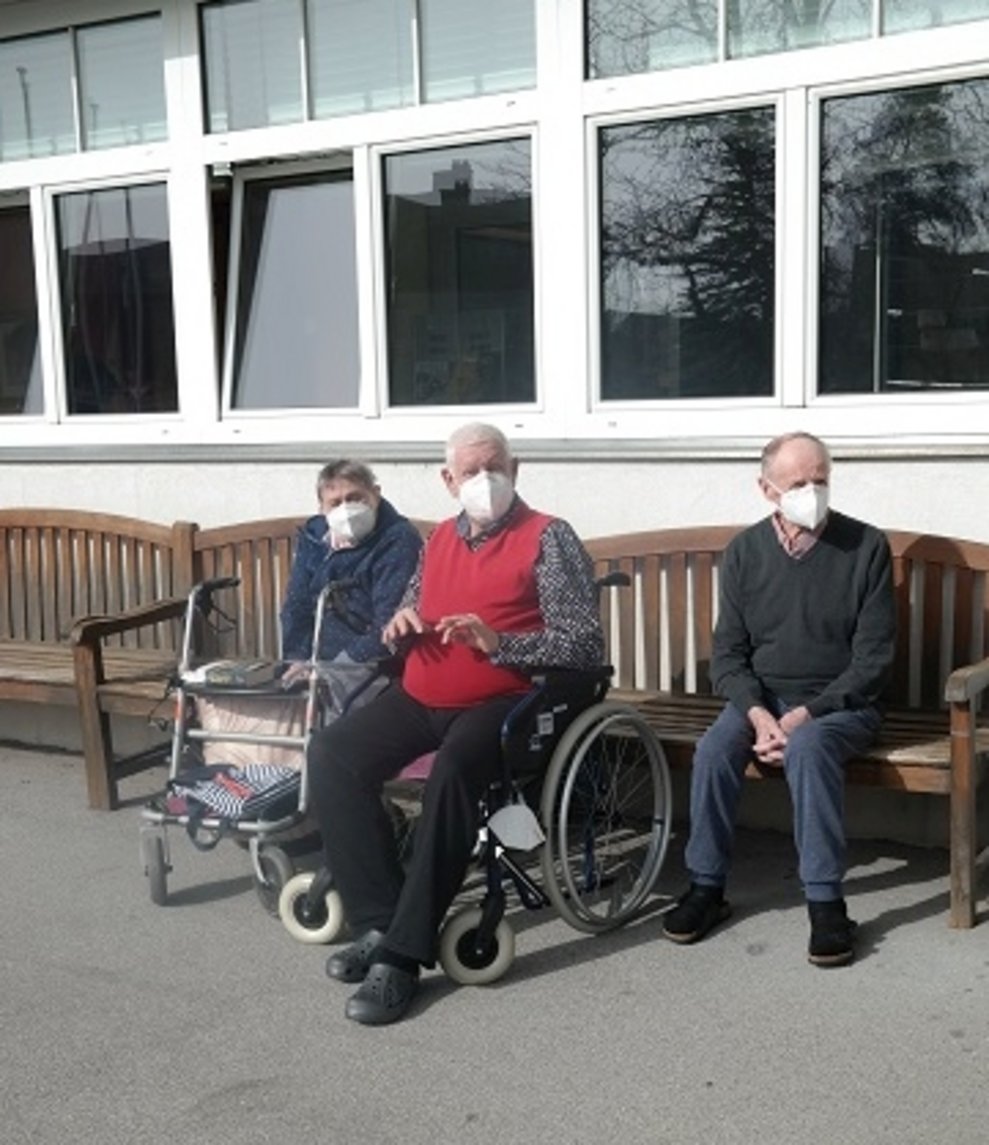 BewohnerInnen sitzen draußen.