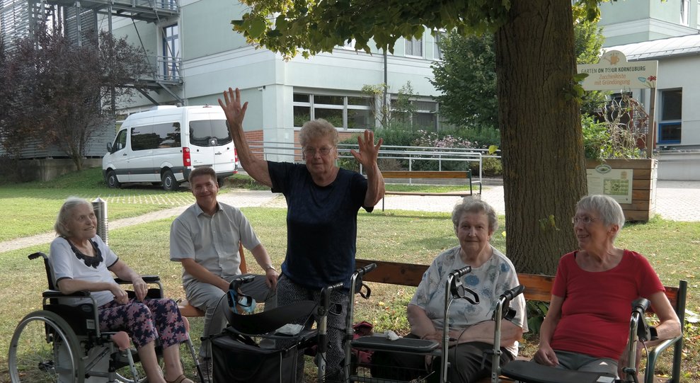 BewohnerInnen sitzen draußen.